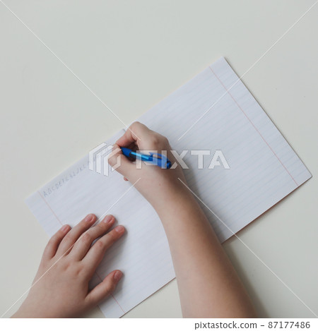 pupil's hands writing in open notebook, top view, copy space 87177486