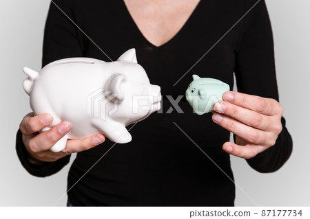 Two piggy bank in a woman's hands Two piggy bank in a woman's hands 87177734