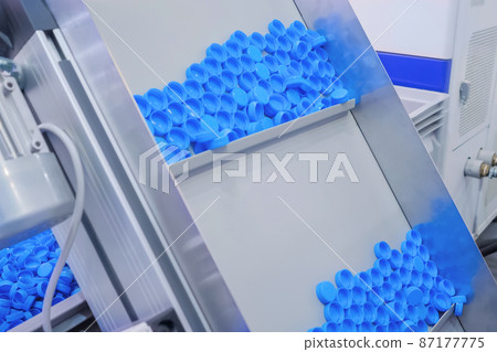 Many blue plastic bottle caps moving on conveyor belt - production line Many blue plastic bottle caps moving on conveyor belt - production line 87177775