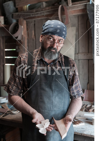 Spoon master in his workshop with wooden products and tools 87177986