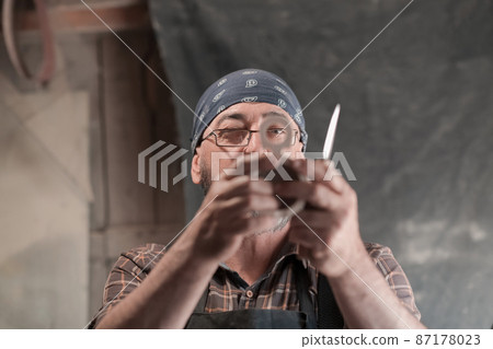 Spoon craft master in his workshop with handmade wooden products and tools working Spoon craft master in his workshop with handmade wooden products and tools working 87178023