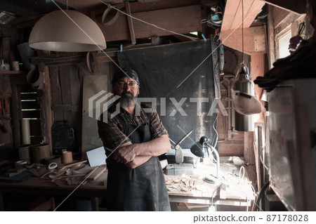 Spoon craft master in his workshop with handmade wooden products and tools Spoon craft master in his workshop with handmade wooden products and tools 87178028