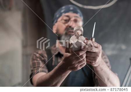 Spoon craft master in his workshop with handmade wooden products and tools working Spoon craft master in his workshop with handmade wooden products and tools working 87178045