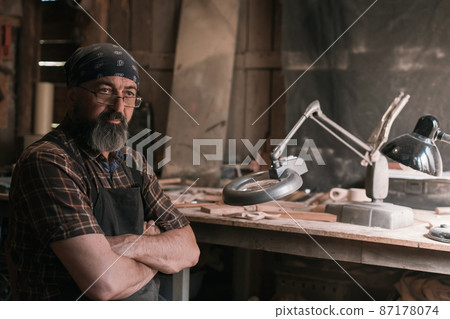 Spoon master in his workshop with wooden products and tools 87178074