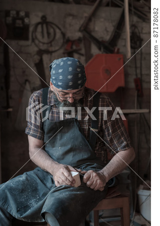 Spoon craft master in his workshop with handmade wooden products and tools working Spoon craft master in his workshop with handmade wooden products and tools working 87178082