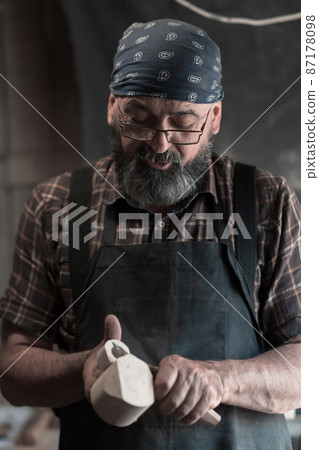Spoon master in his workshop with wooden products and tools 87178098