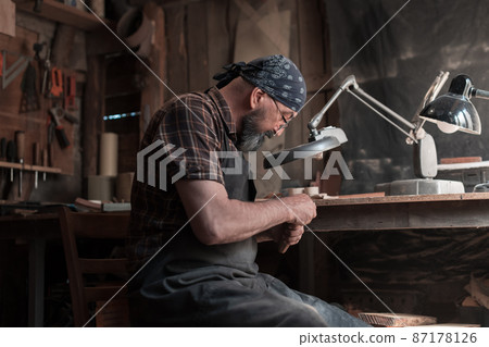 Spoon master in his workshop with wooden products and tools Spoon master in his workshop with wooden products and tools 87178126