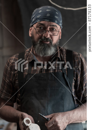 Spoon master in his workshop with wooden products and tools Spoon master in his workshop with wooden products and tools 87178133