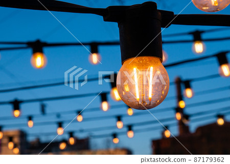 Light bulbs on the evening blue sky. 87179362