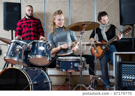Music band with happy girl drummer rehearsing 87179770