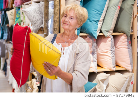 Mature woman choosing pillow at household shop Mature woman choosing pillow at household shop 87179942