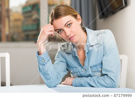 Upset woman sitting at table 87179999