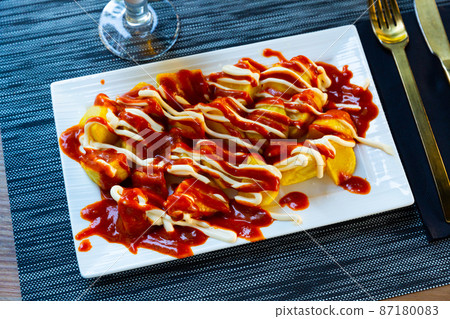 Spanish dish Patatas bravas with hot sauce 87180083