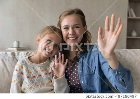 Happy sweet daughter kid and young mom waving hand hello 87180497