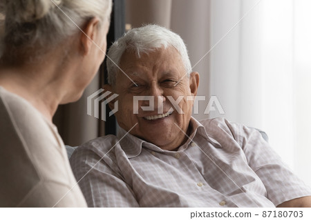 Happy elderly man talking to wife, female carer at home Happy elderly man talking to wife, female carer at home 87180703