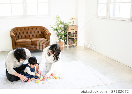A young family playing with a baby in a family group, a bird's-eye view, wide-angle copy space available 87182672