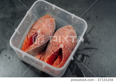 Top view of Fresh frozen raw red salmon fish. Frozen salmon steaks in a plastic box or container Top view of Fresh frozen raw red salmon fish. Frozen salmon steaks in a plastic box or container 87183208