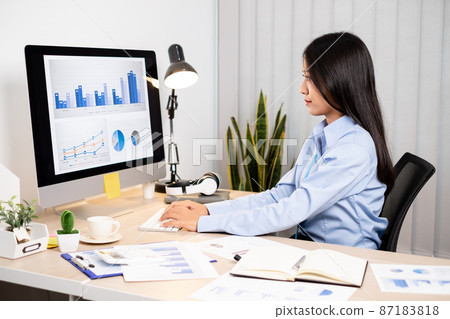Asian woman working on a laptop with a cheerful and happy smile while working at the office 87183818