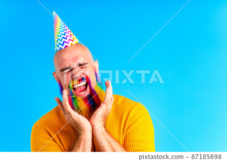happy man with colorful beard wear horn on head in blue studio background happy man with colorful beard wear horn on head in blue studio background 87185698