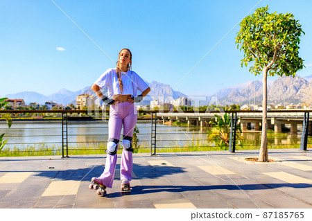 Happy woman with long blonde braids hair on the roller-skate in the park beach and mountain background Happy woman with long blonde braids hair on the roller-skate in the park beach and mountain background 87185765