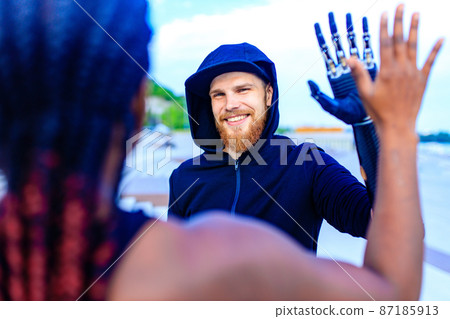 man with arm prosthesis in sports clothing ready for morning workout outdoors. Disabled sport concept man with arm prosthesis in sports clothing ready for morning workout outdoors. Disabled sport concept 87185913