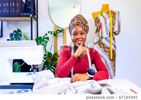 tanzanian woman with snake print turban over hear working in dressmaking shop tanzanian woman with snake print turban over hear working in dressmaking shop 87185945