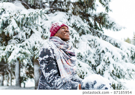 african american man in a snowy winter woodland with snowflakes falling from spruce and fir forest african american man in a snowy winter woodland with snowflakes falling from spruce and fir forest 87185954
