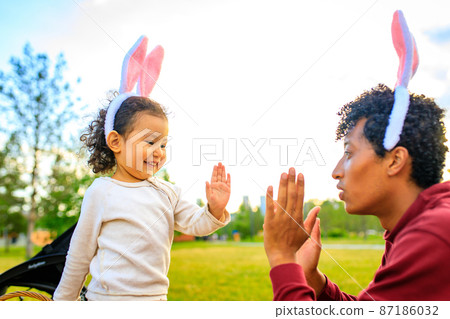 latin hispanic father and mixed race little girl playing rabbit and hare outdoor 87186032