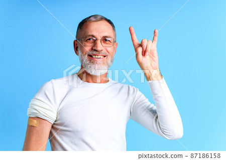 Healthy mature man getting vaccinated immunity blue background studio Healthy mature man getting vaccinated immunity blue background studio 87186158
