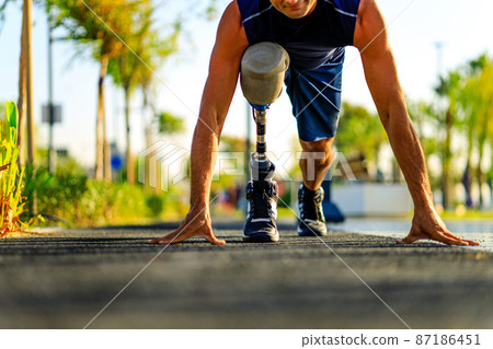 disabled athlete man with prosthetic leg starting to run at the beach on a treadmill outdoors at sunset 87186451