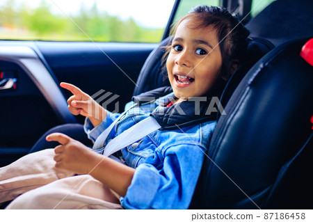 mixed race baby girl in car seat with fastened belt 87186458