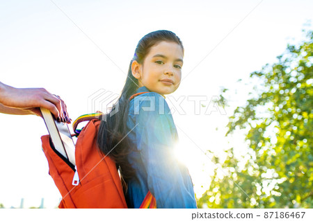 Smiling indian student girl wearing school backpack and blue t-shirt in park Smiling indian student girl wearing school backpack and blue t-shirt in park 87186467