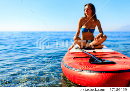 beautiful woman practising yoga on paddle sup surfboard beautiful woman practising yoga on paddle sup surfboard 87186469