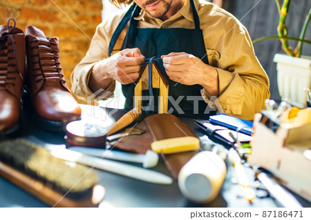 skilled shoemaker make a leather shoes in workshop skilled shoemaker make a leather shoes in workshop 87186471