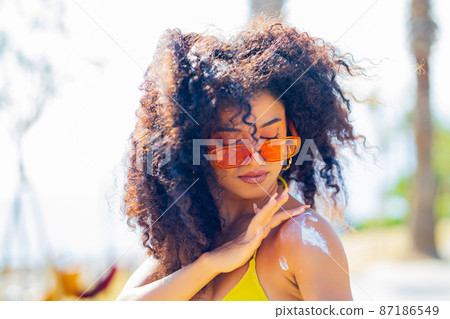 brazilian curly beautiful woman protect her skin with sun block cream at sunny day brazilian curly beautiful woman protect her skin with sun block cream at sunny day 87186549