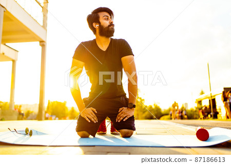 hispanic man in black cotton t-shirt ready to yoga at sunset in summer park outdoor golden lights 87186613