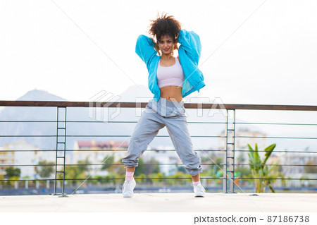 mixed race curly woman enjoying dance at sunset in beach mixed race curly woman enjoying dance at sunset in beach 87186738