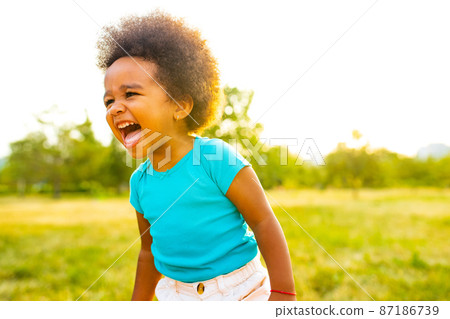 adorable small mixed race girl walking alone in park at sunset time adorable small mixed race girl walking alone in park at sunset time 87186739