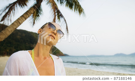 Close up portrait woman in a white tunic shirt on beach, near st 87188146