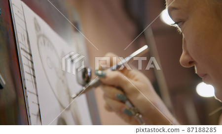 Woman artist learns to paint with airbrush with acrylic dye, paper and easel. Concept modern art, airbrushing, aerography, graffiti, aerosol spray 87188285