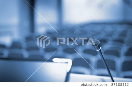 Rostrum with microphone and computer in conference hall, blue toned 87188312