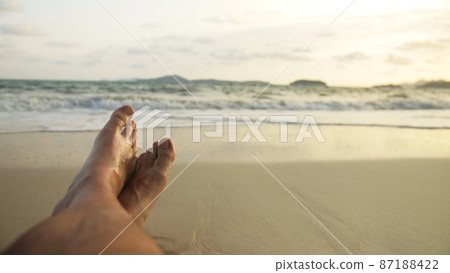 The man feet relaxed are lying on the sandy beach and washed by The man feet relaxed are lying on the sandy beach and washed by 87188422