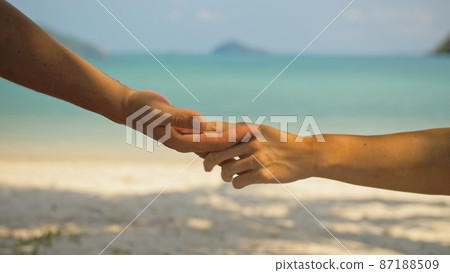 Hands of flirting young man and woman touching on sea beach Hands of flirting young man and woman touching on sea beach 87188509