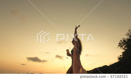 Woman stand on a reef rock stone in sea on sunset. Girl on beach Woman stand on a reef rock stone in sea on sunset. Girl on beach 87188581