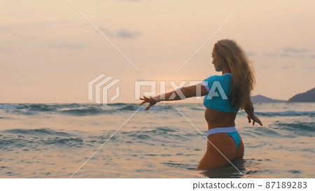 Woman standing on water sea. Girl stand in turquoise swimsuit. Freedom paradise holiday vacation summer beach, seaside landscape concept Woman standing on water sea. Girl stand in turquoise swimsuit. Freedom paradise holiday vacation summer beach, seaside landscape concept 87189283