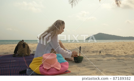 The cheerful woman in holding and eating slices of watermelon on tropical sand beach sea. Portrait attractive girl spend summer weekend. The cheerful woman in holding and eating slices of watermelon on tropical sand beach sea. Portrait attractive girl spend summer weekend. 87189382