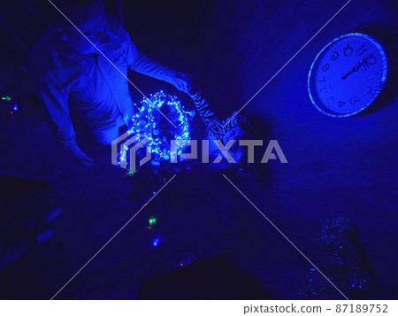 The family fast and fanny decorates the Christmas tree. Top view. Time on the clock is 23.45 on wall. Happy dad, mom, daughter are run around tree. The family fast and fanny decorates the Christmas tree. Top view. Time on the clock is 23.45 on wall. Happy dad, mom, daughter are run around tree. 87189752