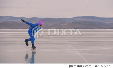 The child train on ice professional speed skating. The girl skates in the winter in sportswear, sport glasses, suit. Outdoor slow motion. The child train on ice professional speed skating. The girl skates in the winter in sportswear, sport glasses, suit. Outdoor slow motion. 87189756