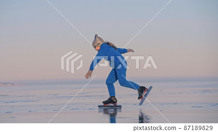 The child train on ice professional speed skating. The girl skates in the winter in sportswear, sport glasses, suit. Outdoor slow motion. The child train on ice professional speed skating. The girl skates in the winter in sportswear, sport glasses, suit. Outdoor slow motion. 87189829