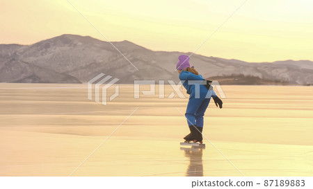 The child train on ice professional speed skating. The girl skates in the winter in sportswear, sport glasses, suit. Outdoor slow motion. The child train on ice professional speed skating. The girl skates in the winter in sportswear, sport glasses, suit. Outdoor slow motion. 87189883